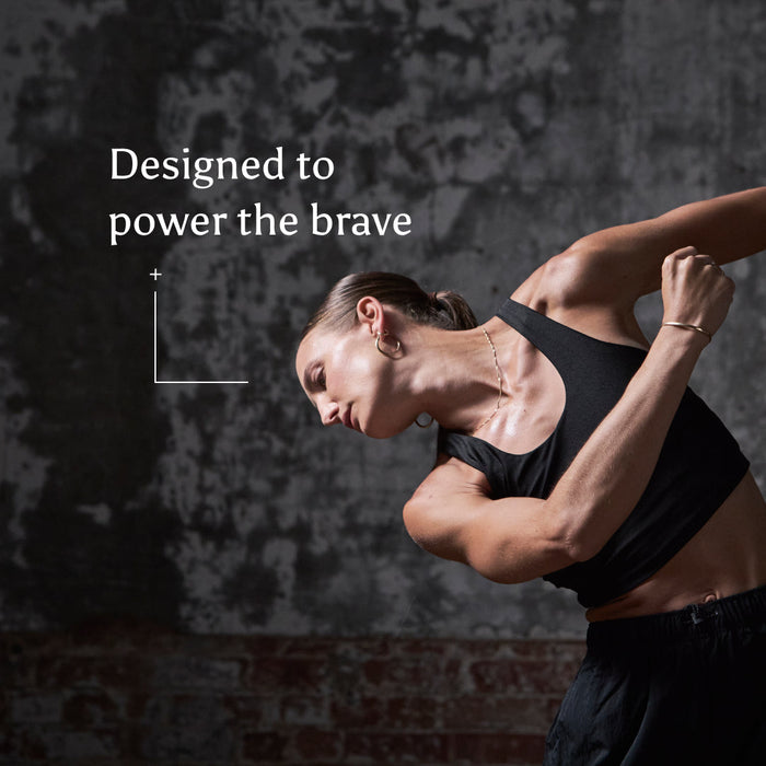 A strong woman in athletic wear poses dynamically against a textured, dark background. Text beside her reads, True Creatine+: Designed to power the brave—with support for muscle health.