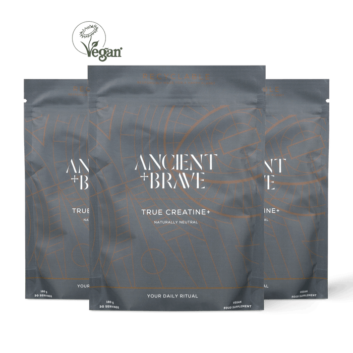 Three stand-up pouches of Ancient + Brave True Creatine+ arranged in a fan shape against a solid black background, with a Vegan logo at the top left.