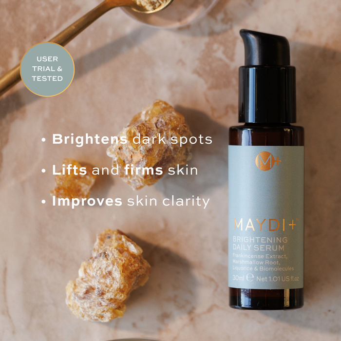 Maydi+ brightening daily serum bottle with ingredients on a neutral background. brightens dark spots, lifts and firms skin, improves skin clarity.