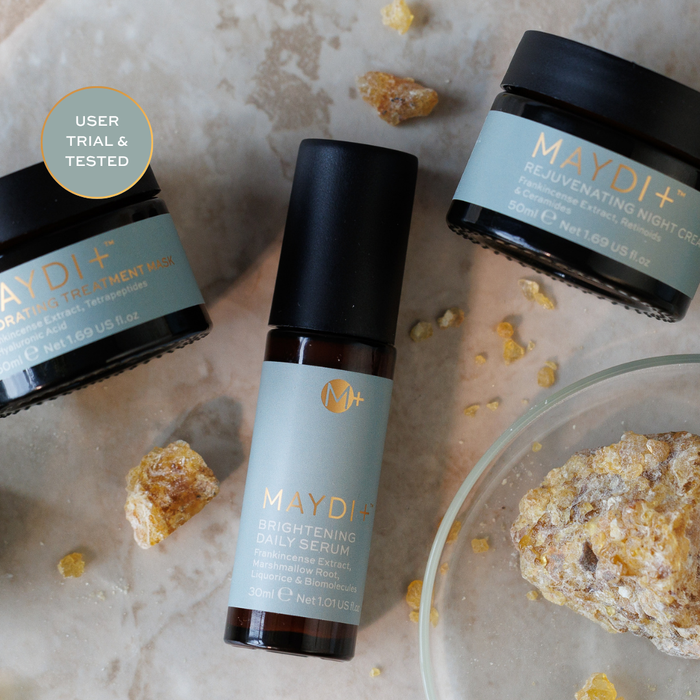 Maydi+ skincare products including a serum, cream, and night cream on a textured surface with natural ingredients.