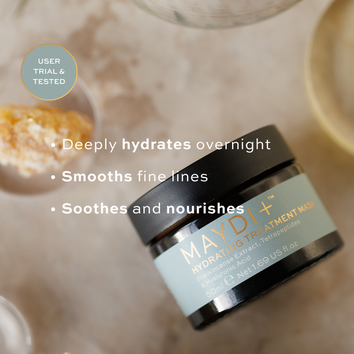 Maydi+ hydrating treatment mask jar with product benefits text on a blurred background. hydrates overnight, smooths fine lines, soothes and nourishes.