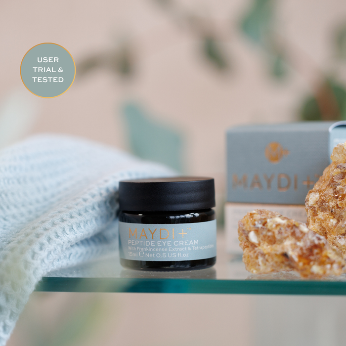 Maydi+ peptide eye cream jar on a table with a blurred background